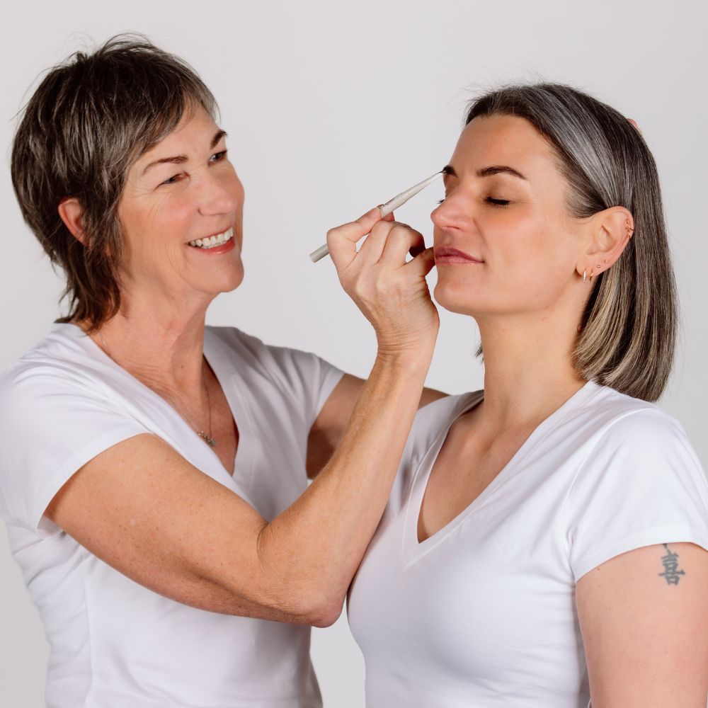 Image shows older lady applying the Reform Cosmetics Brow Define Pencil in medium brown